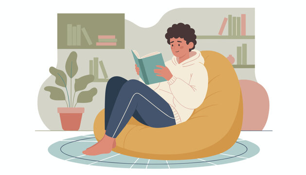 Relaxed young man comfortably sitting on a yellow bean bag chair and reading an interesting book in his cozy living room.
