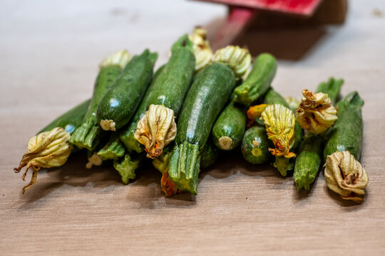 Fresh green zucchini with flowers displayed on a counter in a farmer agricultural open air market