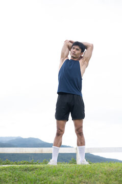Athletic Asian Man Performing Triceps Stretch Outdoors