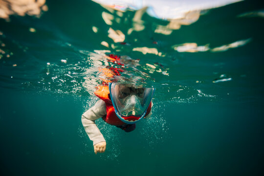 Child wearing full face snorkel mask underwater