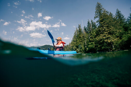 Split level view of child kayaking on a calm lake