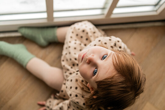 Cute toddler girl with big blue eyes looking up at camera