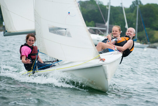 Three teenage girls smile while sailing together