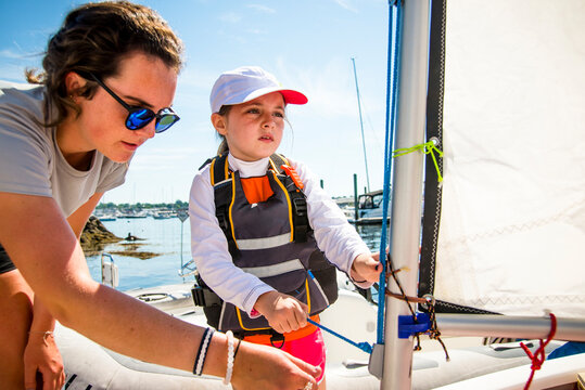 Sailing instructor teaches child how to rig a sailboat