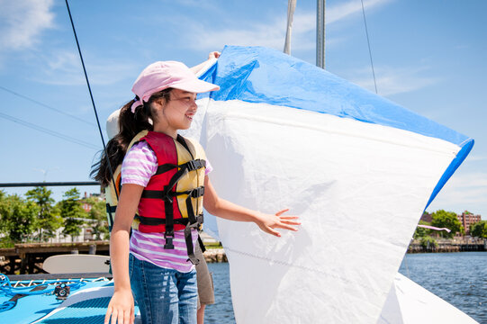 Young girl in life jacket learning to sail