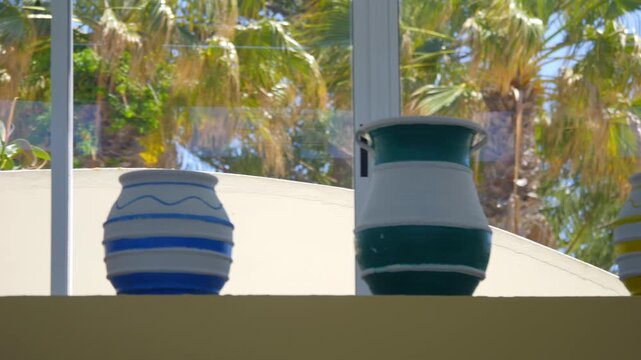 Colorful Greek pots displayed against a backdrop of palm trees, showcasing traditional Greek pottery in 4K slow motion 120fps