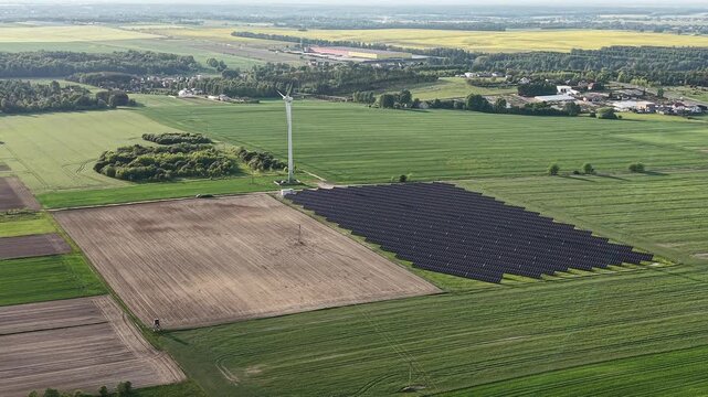 Wind Turbine Above Solar Panel Farm in Rural Agricultural Landscape