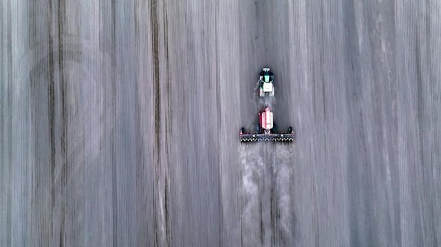 High angle drone view of a tractor plowing dry agricultural field
