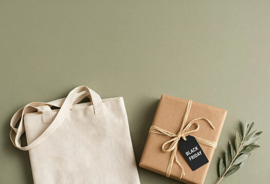 Black friday shopping concept with a canvas tote bag and a gift box on a sage green background