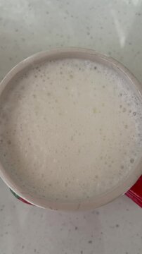 Close up of milk foam bubbles popping in a coffee mug, showcasing the process of preparing a hot cappuccino or latte macchiato for breakfast in a cafe or at home