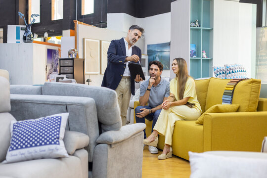 Couple consulting salesperson buying furniture in store