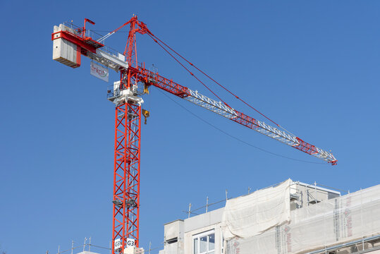 Nancy, France - March 31st 2019 : View on a red and white hammerhead top-slewing tower crane Potain MD 265 B1 J12 on a construction site for the construction of a building.