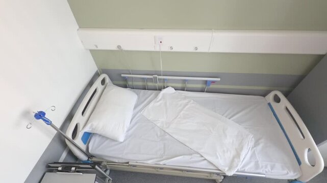 An empty hospital bed is made with white linen