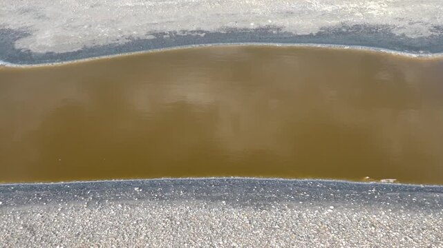 Salmon-colored water in a salty river in the desert. The color of the water due to Dunaliella salina and Salinibacter ruber. Pink lake, pink river. A dead river and lifeless shores