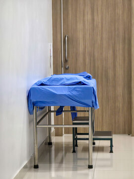 Blue surgical drape neatly covering stainless steel examination table in clinical hallway conveying calm and sterile atmosphere