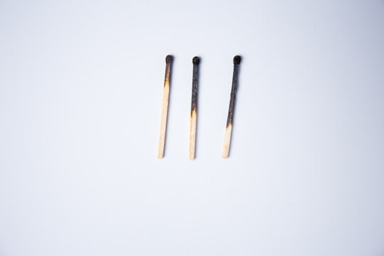 Three used, burnt matchsticks against a white background