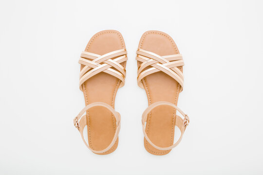 New light brown female sandals with straps on light gray table background. Closeup. Flat lay. Top down view.