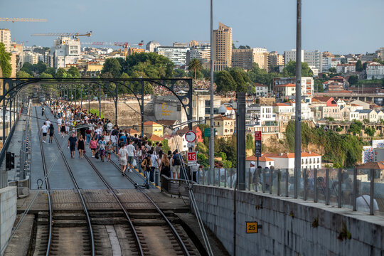 Vila Nova de Gaia, Portugal - 28 July 2026: View of the Dom Luis I Bridge crowded with pedestrians on the tram tracks, with the historic cityscape of Porto in the background.