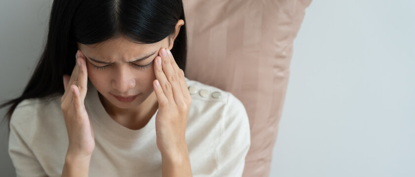 Headache, female having migraine pain, bad health, Asian woman feeling stress and headache, Office syndrome, sad tired touching forehead having migraine or depression, irritated girl, sadness grief