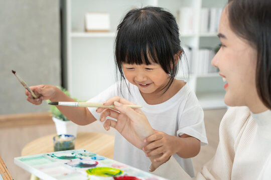 Happy Asia mother playing learning paint for little girl. Funny family is happy and excited in the house. Mother and daughter  having fun spending time together. Holiday, Activity