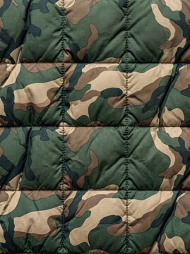 Close up of a quilted camouflage fabric with stitched puffy squares in green and brown tones, showing a padded military inspired texture ideal for outdoor gear and apparel textile design.