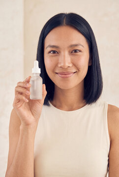 Smiling woman holding a frosted glass dropper bottle for skincare serum product mockup and beauty packaging banner use