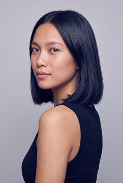Studio portrait of confident woman with bob haircut looking over shoulder for headshot background and professional profile