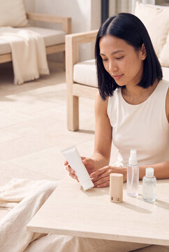 Woman selecting skincare products at home on a neutral minimalist table for routine product display and lifestyle banner