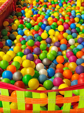 Colorful plastic balls filling a children's ball pit in an indoor playground. Bright multicolored spheres creating a vibrant full-frame background with yellow, blue, green, red, purple, orange, pink, 