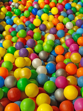 Colorful plastic balls filling a children's ball pit in an indoor playground. Bright multicolored spheres creating a vibrant full-frame background with yellow, blue, green, red, purple, orange, pink, 