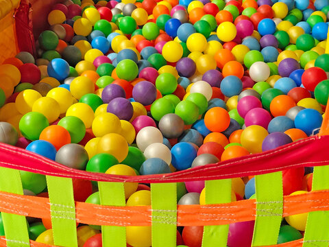 Colorful plastic balls filling a children's ball pit in an indoor playground. Bright multicolored spheres creating a vibrant full-frame background with yellow, blue, green, red, purple, orange, pink, 