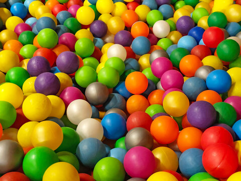 Colorful plastic balls filling a children's ball pit in an indoor playground. Bright multicolored spheres creating a vibrant full-frame background with yellow, blue, green, red, purple, orange, pink, 