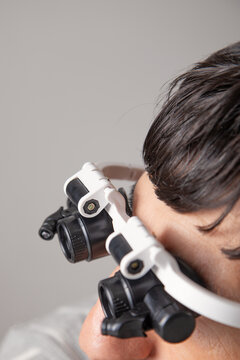 Man wearing optical microscope eyeglasses in grey background.