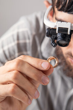 Man looking at golden jewelry through a microscope.