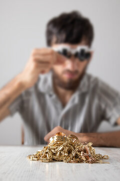 Man looking at golden jewelry through a microscope.