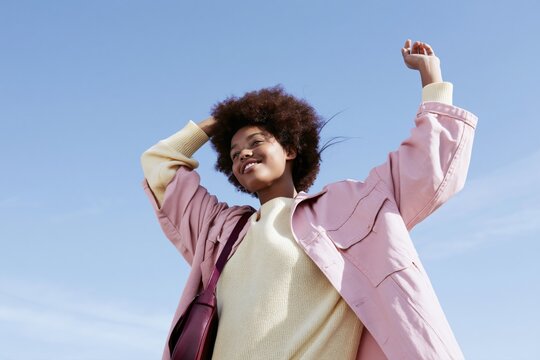 Happy young woman enjoying freedom outdoors under blue sky, positive lifestyle, confidence, energy and carefree summer mood