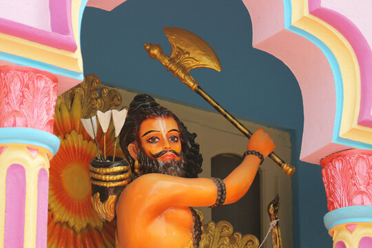 Vibrant colorful statue of Hindu god Parashurama avatar of Vishnu raising an axe in a temple niche.