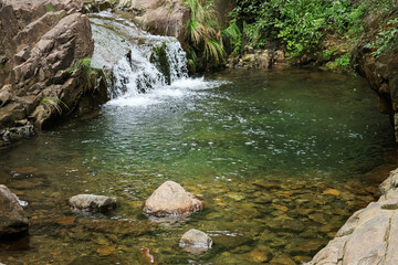 Small Waterfall and Clear Rocky Pool in Lush Forest © LuuDieuThanh