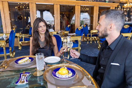 Glamorous couple enjoying fine dining and champagne toast in luxury restaurant