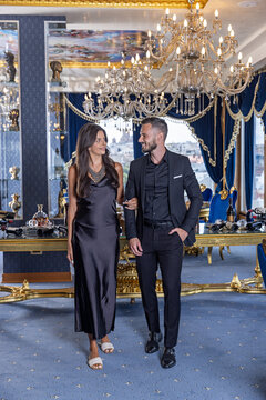 Elegant couple in formal attire walking arm in arm through a luxury room