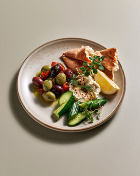 Eastern Mediterranean mezze plate with marinated olives soft cheese cucumber herbs and torn flat bread showcasing quiet luxury dining