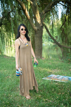 Portrait of a woman artist painter outoor painting by the river in sunglasses 