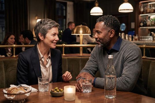 Professionals have conversation at a restaurant in the evening with drinks on the table
