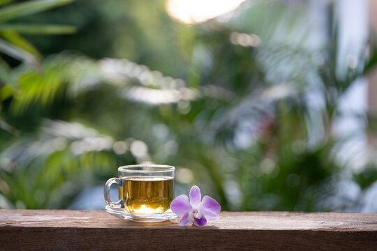Tea in a glass up and purple orchid flower arranged on wood table