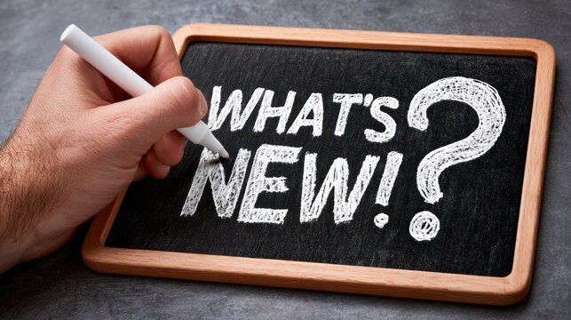 Hand writing whats new on a chalk board with a white marker