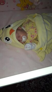 A small baby is sleeping and sucking a pacifier.