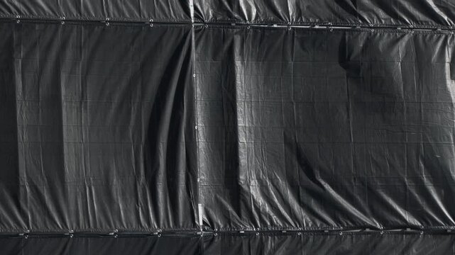 修繕工事中のマンションの黒い足場メッシュシートが風に揺れる背景素材

