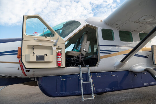 Nairobi, Nairobi County, Kenya - 23 December 2023: View of a light aircraft parked on the tarmac with its cabin door open, showing interior seats, a fire extinguisher, and steps.