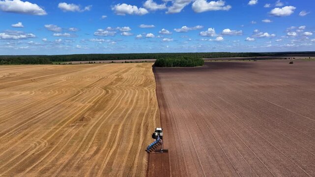 High angle drone view of a tractor plowing dry agricultural field
