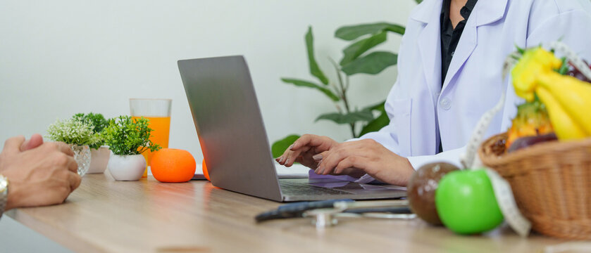 Doctor and patient in medical consultation using laptop for AI health analysis